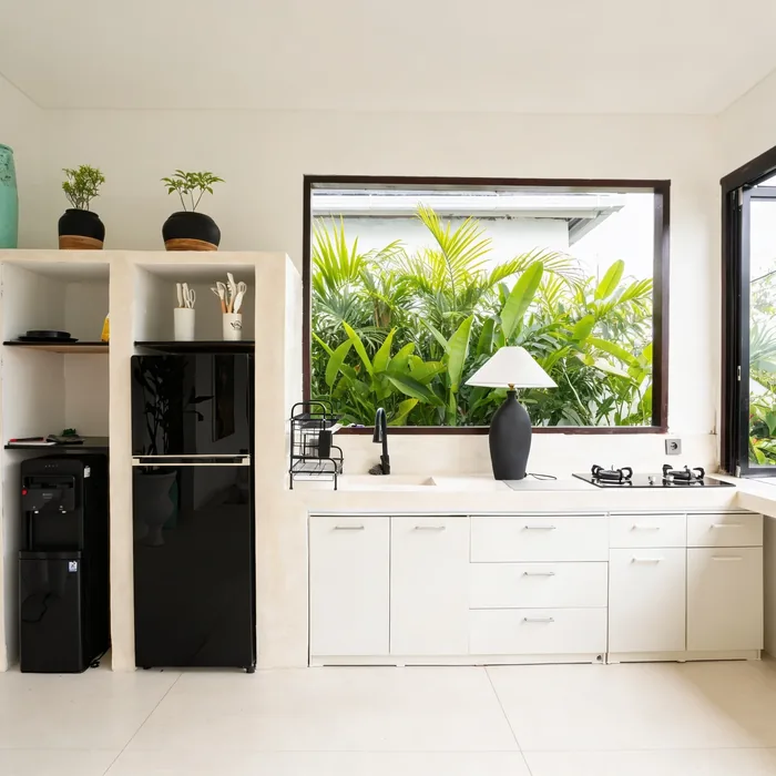 Villa Sayan IV kitchen with white cabinetry, black fridge and jungle-view window
