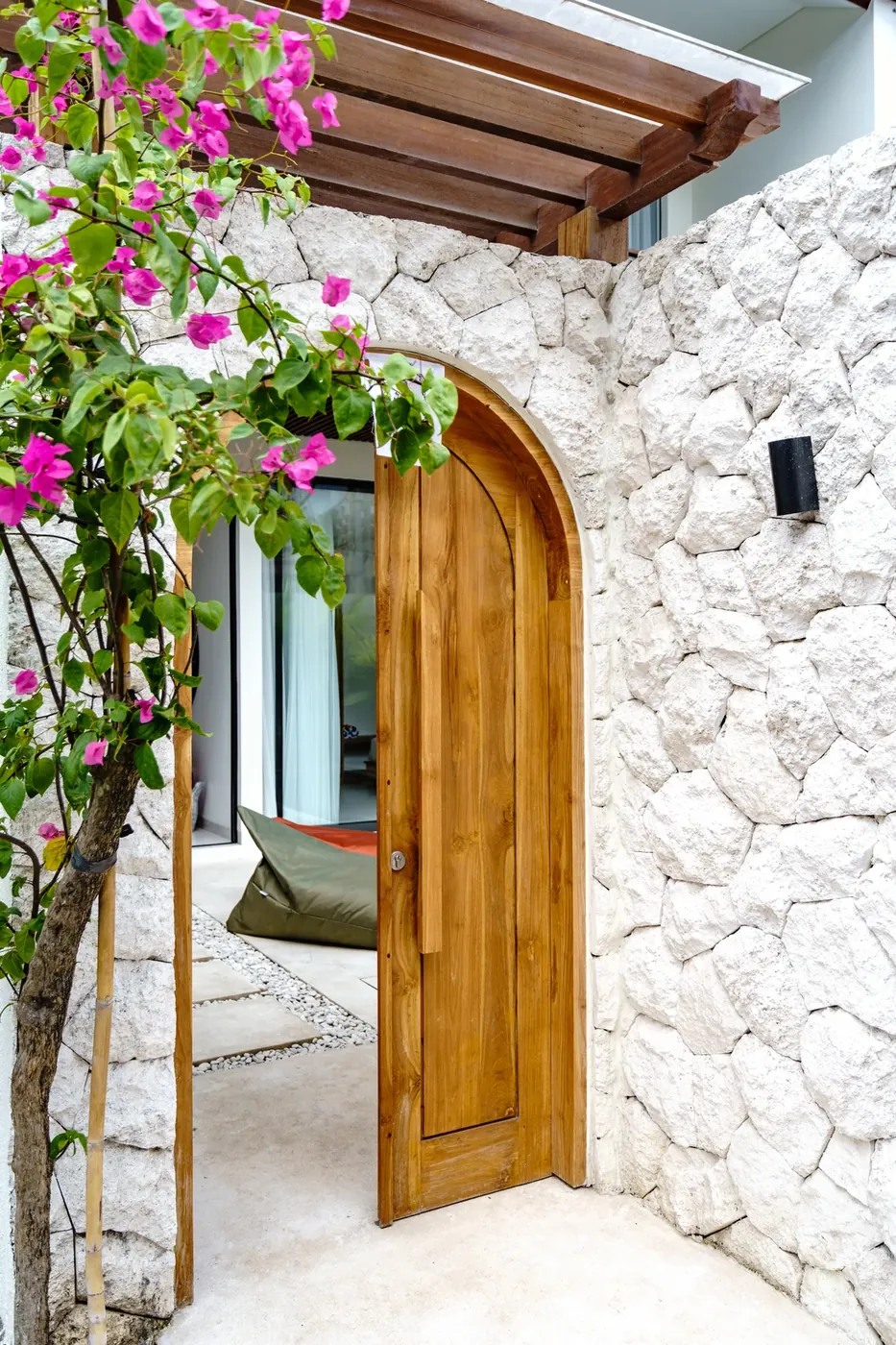 Villa Oasis arched teak entrance door framed by bougainvillea